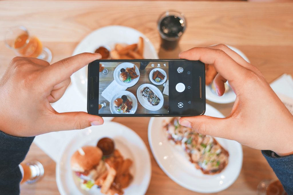 A person taking photograph of a certain restaurant dishes using their phone