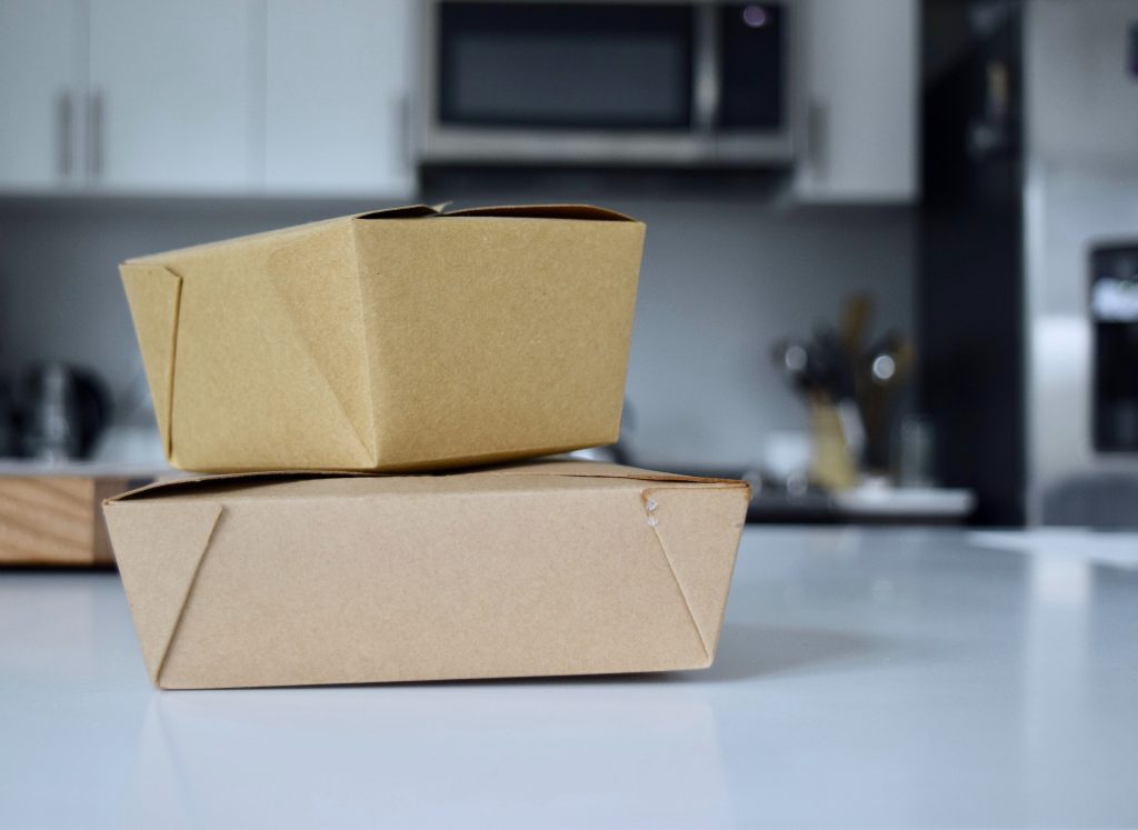 An image showing cardboard boxes containing meals on a restaurant table top.